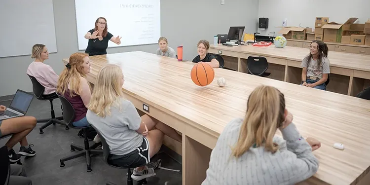 A teacher using a basketball to demonstrate motion to high school age students